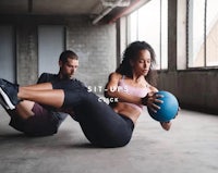two people doing sit ups in a gym