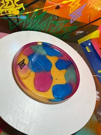 a plate with colorful paint on it is sitting on top of a table