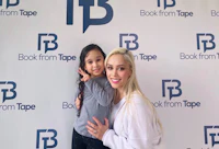 a woman and a little girl posing for a photo in front of a book from tape sign