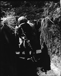 a soldier in a trench with a rifle
