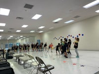 a group of people standing in a room with chairs