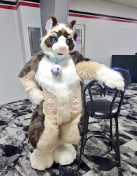 a cat mascot posing in front of a chair