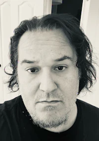 a man in a black shirt is staring at the camera