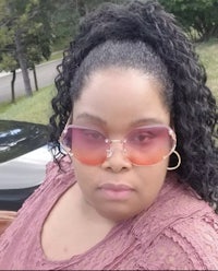 a woman wearing sunglasses in front of a car