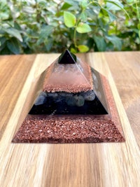 a pyramid with black and brown stones on top of a wooden table