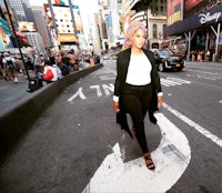 a woman wearing a hijab crossing the street in times square