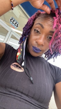 a woman with purple dreadlocks posing for a photo