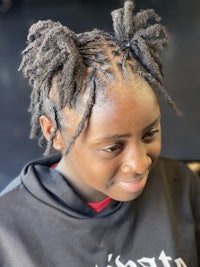a young girl with dreadlocks sitting in a chair