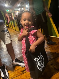 a little girl holding a black tote bag