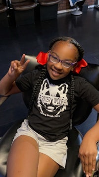 a young girl sitting in a chair at a hair salon