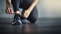 a woman is tying her shoes in a gym