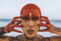 a woman with red hair and tattoos on her face