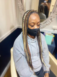 a woman sitting in a chair with braids and a mask on her face