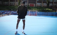 a man in a black hoodie standing on a basketball court