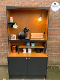 a black cabinet with a coffee maker and mugs