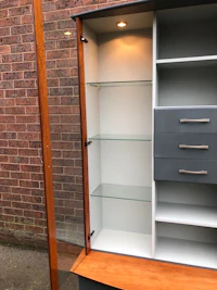 a wooden cabinet with glass shelves and drawers