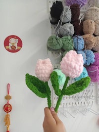 a person is holding a bunch of crocheted flowers