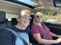 a man and woman smiling in the back seat of a car