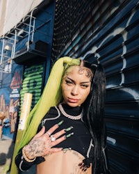 a woman with green hair and tattoos posing in front of a building