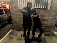 two men standing next to each other in a parking lot