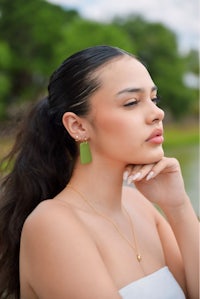 a woman wearing a white dress and green earrings