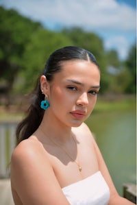 a woman wearing a white dress and turquoise earrings