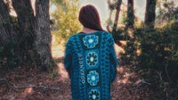 a woman is walking through the woods wearing a blue kaftan
