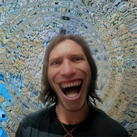 a man with long hair laughing in front of a circular pattern