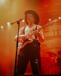a man in a cowboy hat playing a guitar on stage