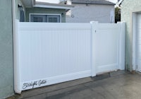 a white gate with a sign on it in front of a house