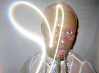 a man with pink hair and a chain around his neck