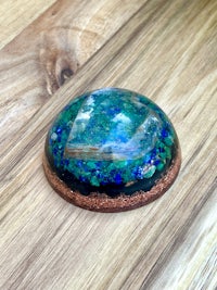 a blue and green glass sphere sitting on a wooden table