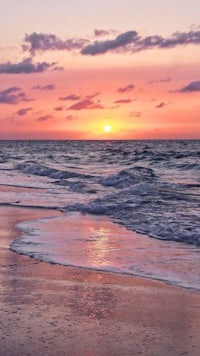 a sunset over the ocean on a beach