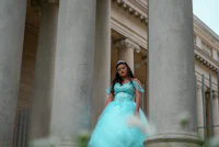 a young woman in a blue dress standing in front of pillars