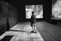 a black and white photo of a man standing in front of a screen