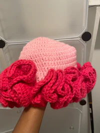a person holding a crocheted pink ruffled hat