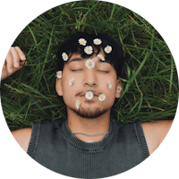 a man laying in the grass with daisies on his face