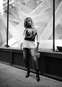 a black and white photo of a woman posing in front of a window