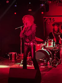 a woman on stage with a microphone and drums