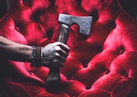 a man holding an axe on a red chair