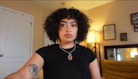 a woman with curly hair in a room with tattoos