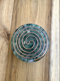 a green and copper spiral on a wooden table