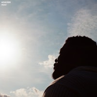a silhouette of a man looking up at the sun