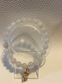 a white bead bracelet with a gold charm