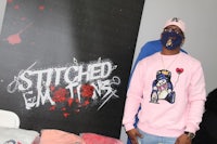 a man in a pink sweatshirt standing next to a display of t - shirts