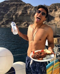 a man holding a plate of food on a boat