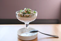 a glass with a salad in it on a wooden table