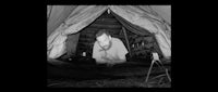 a black and white photo of a man in a tent