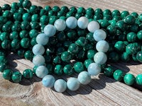 a bracelet with green and white beads on a wooden table