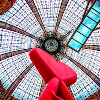 a red chair is sitting under a glass dome